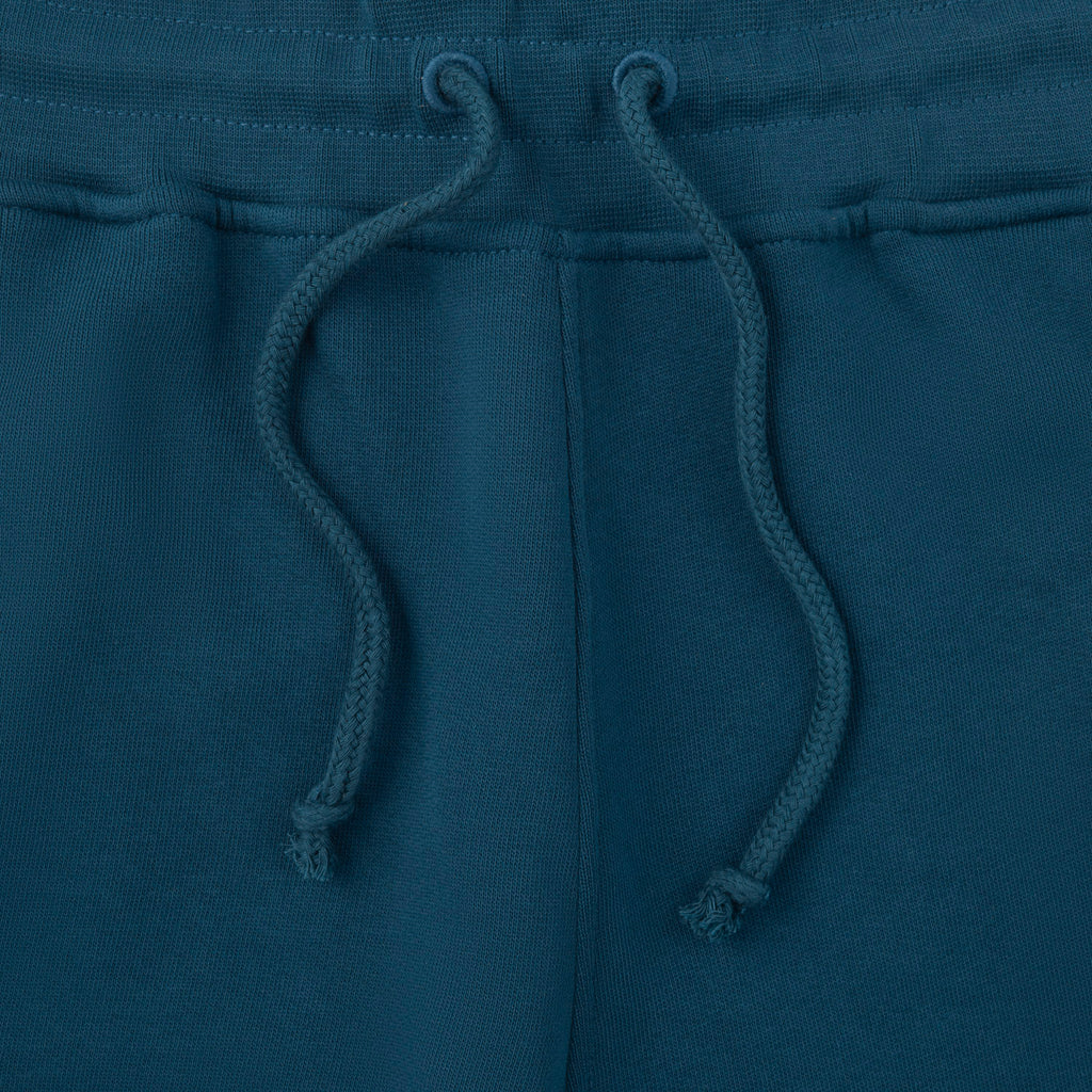 Close-up of blue sweatpants with drawstrings on a matching fabric background